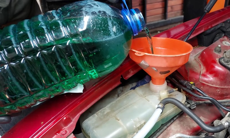 Osoba sipa antifriz iz balona u automobil