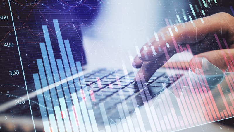 Ruka na tastaturi uz grafike rasta i troškova, kao prikaz stalne kontrole finansija u malom biznisu